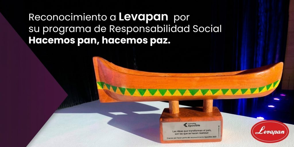 Trofeo de madera con forma de canoa sobre una base que lleva el logo Xposible, junto al texto Reconocimiento a Levapan por su programa de Responsabilidad Social Hacemos pan, hacemos paz.