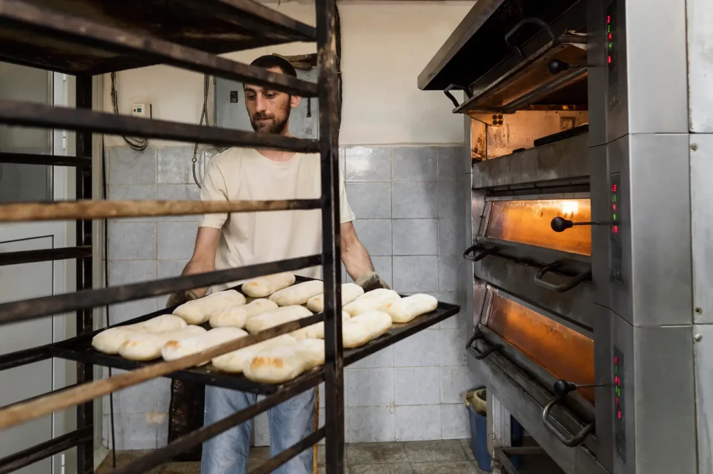 trabajador usando el horno para panadería